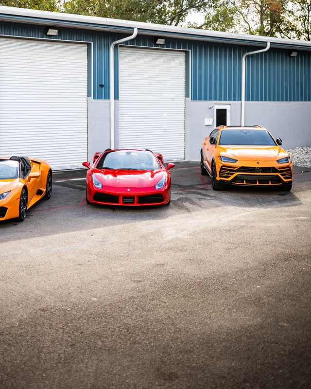 Three cars parked in front of a shop's two bay doors