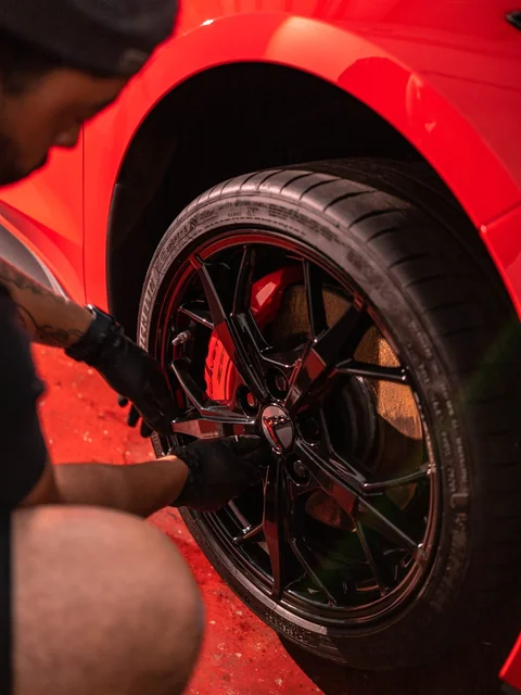 One gloved hand reaching into the spokes of a black wheel