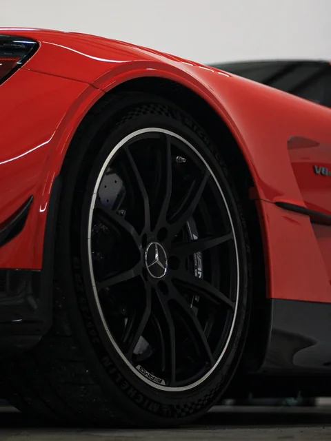 A black wheel beside a red fender