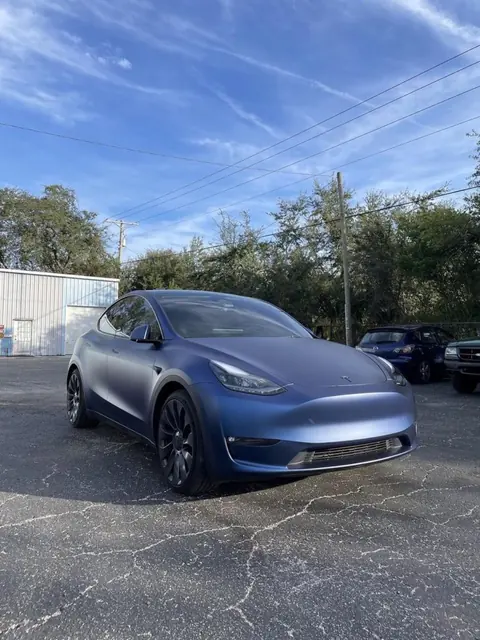 A matte blue crossover parked outside under a clear sky