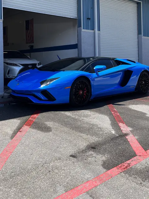 A blue sports car nosing out of an open bay door