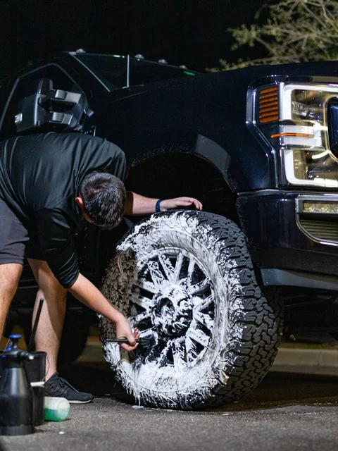 Brushing a foamed truck wheel under the lights at night