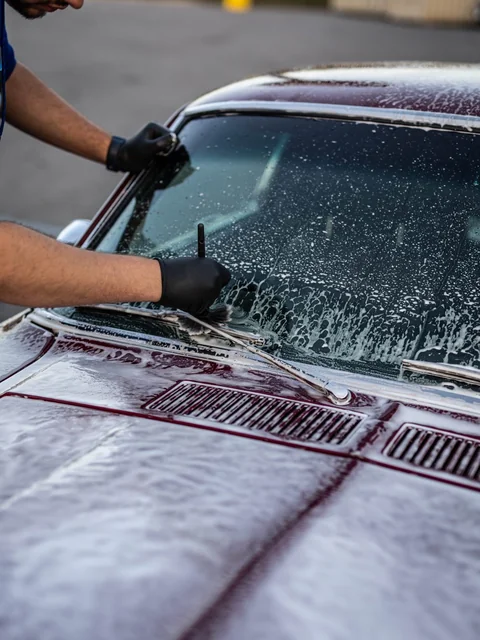 Gloved hands brushing a foamed windshield