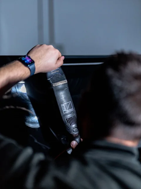 A polisher held over a glossy black hood