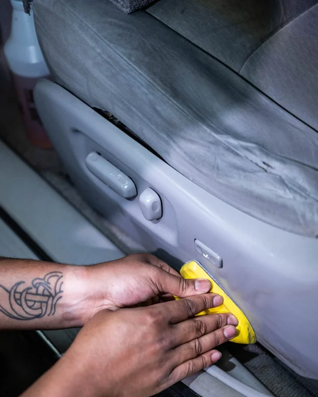 Two hands and a pad on the side of a car seat